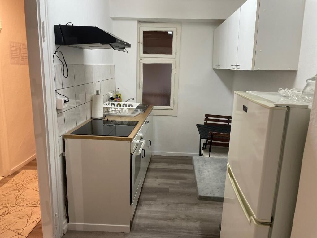 A compact kitchen with a built-in oven, a sink, and a refrigerator.