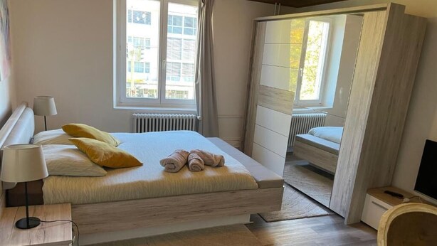 Makuuhuone, jossa on sänky, yöpöytä, lamppu ja ikkunasta avautuva näkymä ulos.