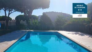 A rectangular swimming pool with clear blue water, surrounded by a tiled deck and a low fence. - Nice Apt with pool near the sea (Le Grau-du-Roi)