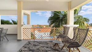 A balcony with wicker chairs, a small table, and a patterned rug.