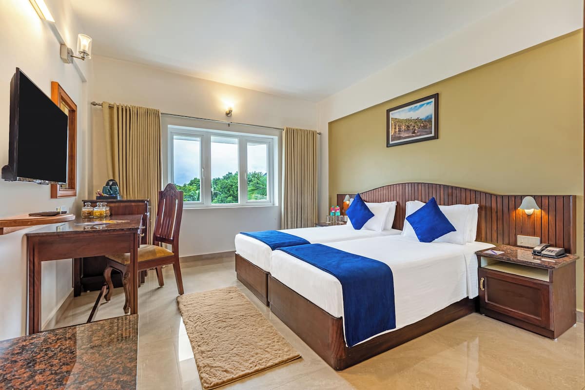 Una habitación de hotel con cama, escritorio, televisión y ventana con cortinas.