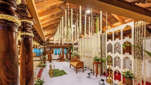 Un'ampia sala con travi in legno, un'area salotto centrale ed elementi decorativi come fiori e piante pendenti.
