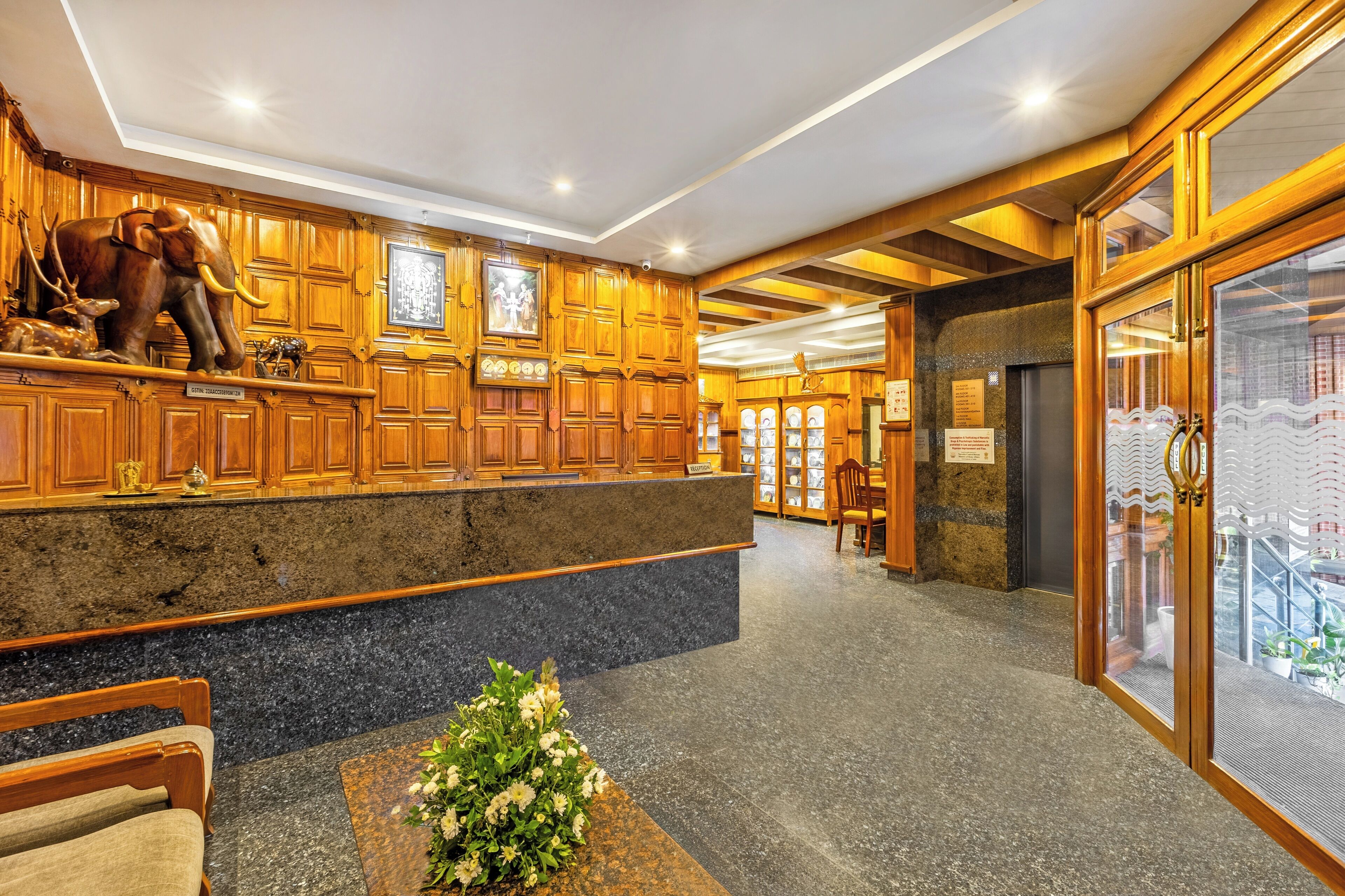 A lobby with wooden paneling, a reception desk, a statue of an elephant, and a flower arrangement.