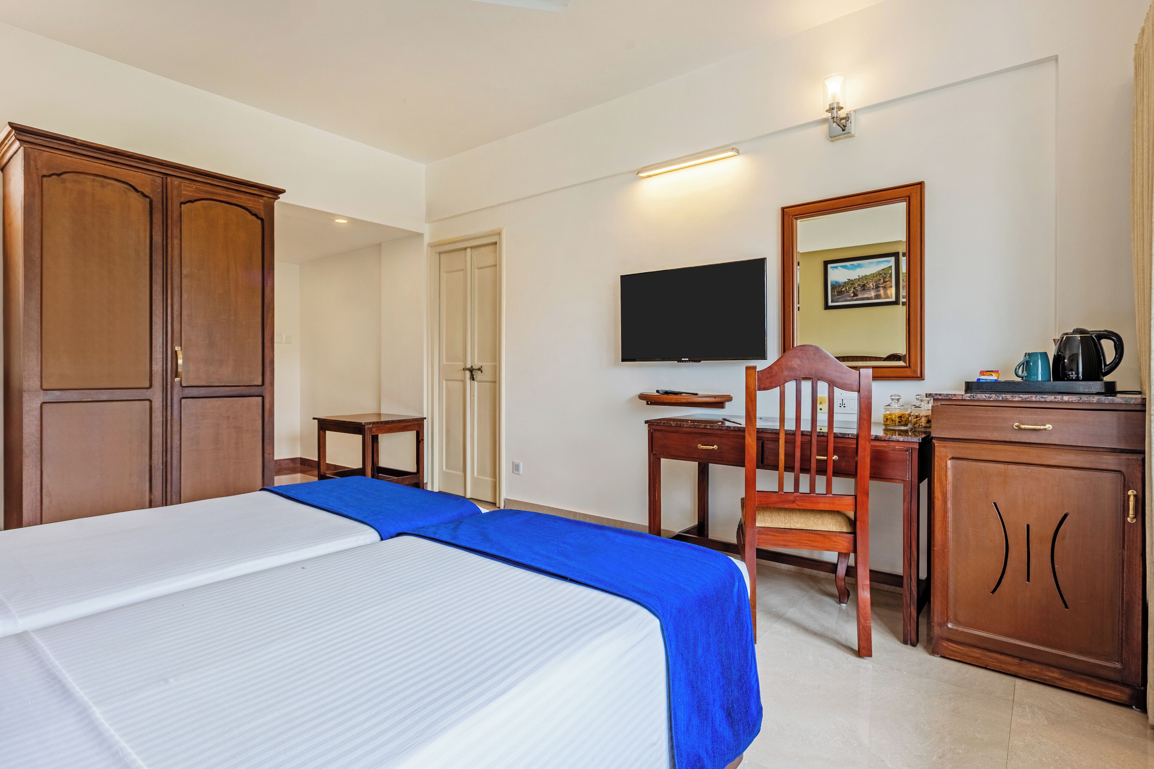 Una habitación de hotel con cama, escritorio, silla, televisor y armario.