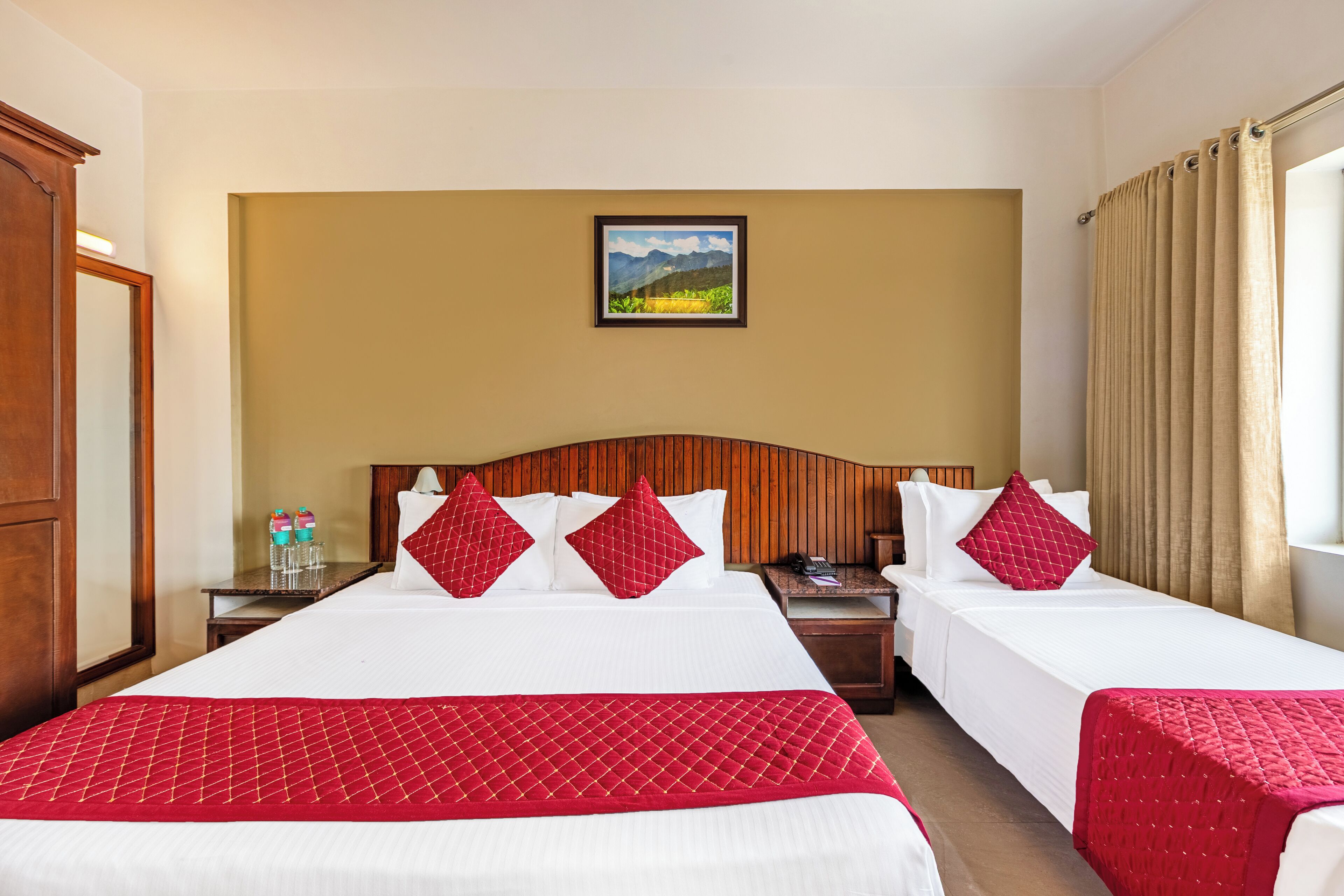 A hotel room with two beds, a wooden headboard, a painting on the wall, and a window with curtains.