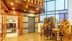 Un'hall con pavimento in marmo, soffitto in legno e una statua di una divinità.