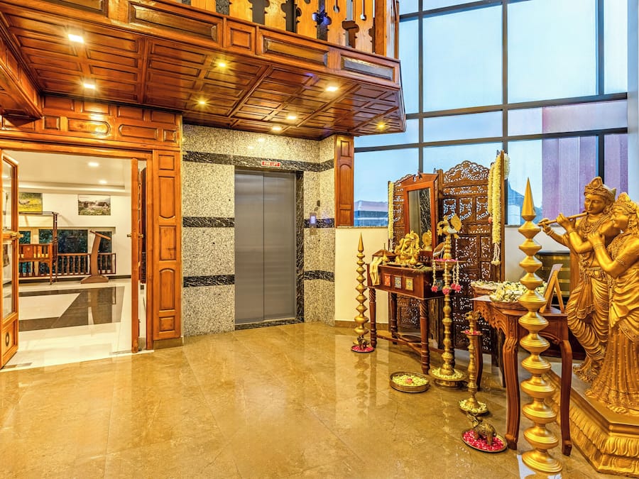 A lobby with a marble floor, wooden ceiling, and a statue of a deity.
