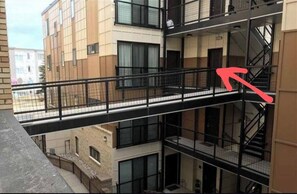 Un edificio a più piani con balconi, una scala e un ponte pedonale.