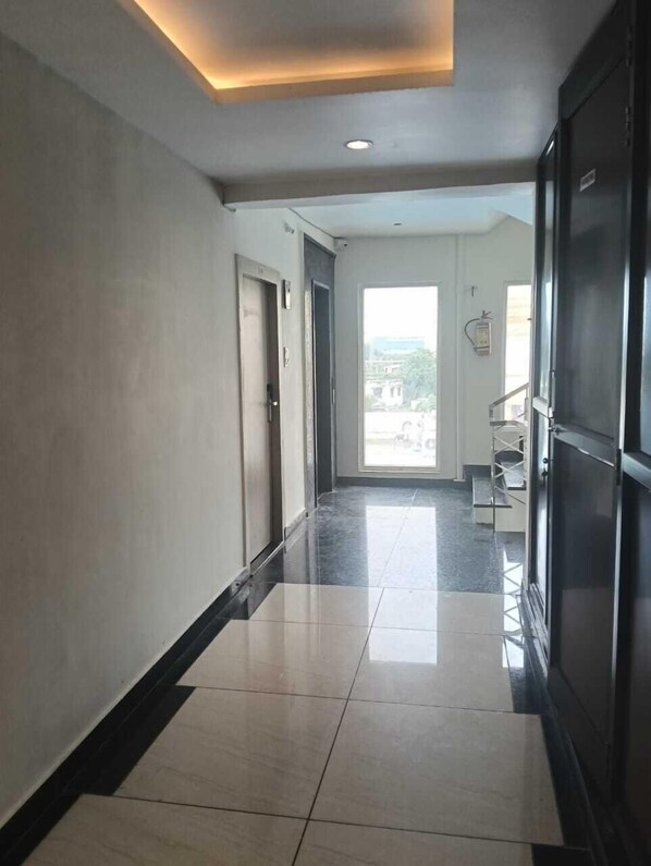 A hallway with a tiled floor and a ceiling light fixture. - MOHANS INN (Haridwar)