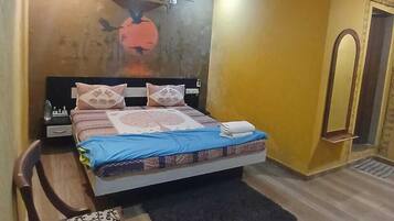 Een slaapkamer met een bed, een stoel, een nachtkastje, een airconditioner en een deur.