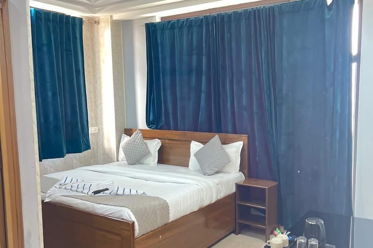 A bedroom with a wooden bed, a nightstand, a desk with a chair, and a ceiling fan.