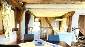 A rustic kitchen with wooden beams, a dining table with chairs, and a small island with a sink. - 4 Person Holiday Home in Uddevalla (Uddevalla)