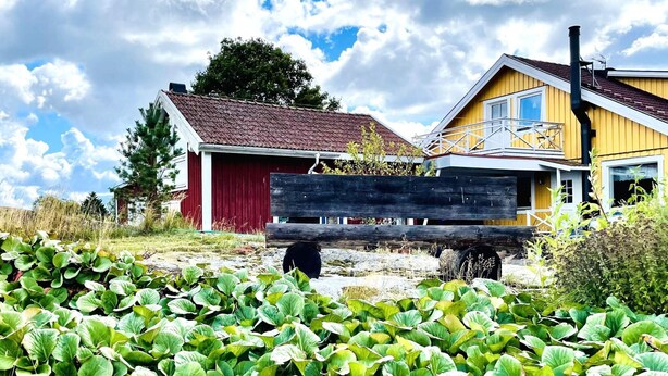 A rural setting with a red barn and a yellow house with a balcony. - 4 Person Holiday Home in Uddevalla (Uddevalla)