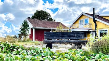 A rural setting with a red barn and a yellow house with a balcony.