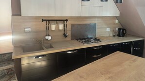 A modern kitchen with a gas stove, stainless steel appliances, and a wooden countertop. - Colonna House a home in the historic center of Genazzano (Genazzano)
