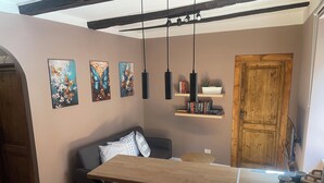 A cozy dining area with a wooden table and benches, a sofa with cushions, and a bookshelf with books and decorative items. - Colonna House a home in the historic center of Genazzano (Genazzano)