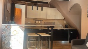 A compact kitchen with a central island, bar stools, and a dining area with a sofa. - Colonna House a home in the historic center of Genazzano (Genazzano)