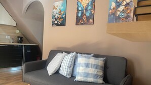 A modern living room with a grey sofa, checkered pillows, and three butterfly-themed paintings on the wall. - Colonna House a home in the historic center of Genazzano (Genazzano)