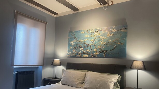 A neatly made bed with folded towels, two bedside lamps, and a painting of a tree on the wall. - Colonna House a home in the historic center of Genazzano (Genazzano)
