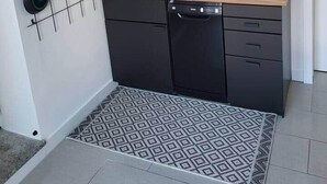 A compact kitchen with black cabinets, a wooden countertop, and a tiled backsplash.