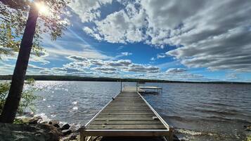 Eine Holzstege ragt in einen See, der bewölktem Himmel entgegenführt.