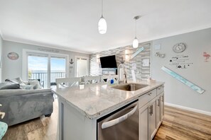 A modern kitchen with a central island, stainless steel appliances, and a dining area with a view.