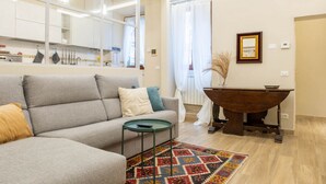 Un salon moderne avec un canapé gris, une petite table ronde et un tapis coloré.