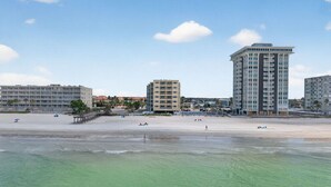 Un hôtel situé en bord de mer, composé de plusieurs bâtiments, avec une plage de sable fin et une eau cristalline.
