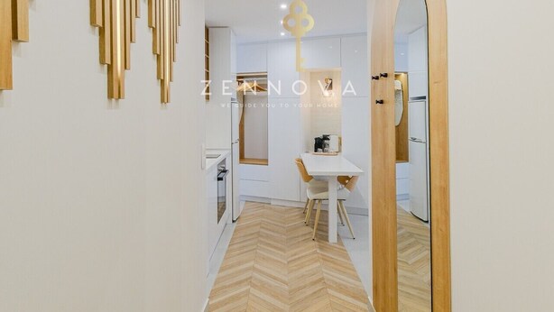 A modern interior with a herringbone-patterned wooden floor, a staircase with wooden slats, and a mirrored wall.