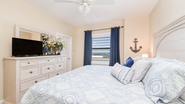 Een slaapkamer met een bed, een dressoir, een televisie en uitzicht op de omgeving.