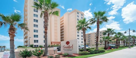 A hotel with a sign indicating private residential condominiums, palm trees, and a clear blue sky.
