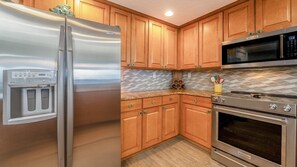 A kitchen with wooden cabinets, a stainless steel refrigerator, a built-in microwave, and a stainless steel oven.