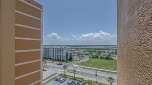Un immeuble de grande hauteur offrant une vue sur un parking, une route et une étendue d’eau lointaine.