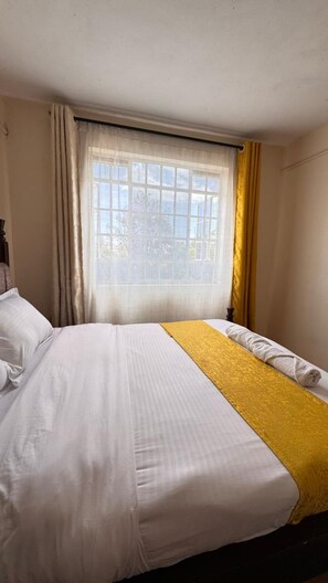 Une chambre d’hôtel avec un lit, une fenêtre avec des rideaux et une vue sur l’extérieur.