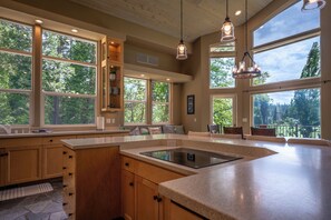 A kitchen with large windows, wooden cabinets, and a central island.