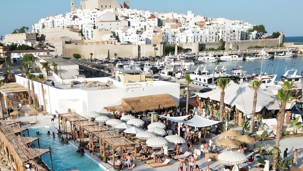 Ein Resort mit mehreren Schwimmbecken, Außenbereich zum Sitzen und Blick auf die Stadt.