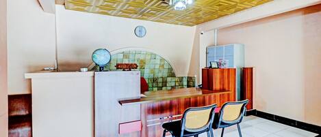 A reception area with a wooden reception desk, two chairs, a clock, and a tiled floor.