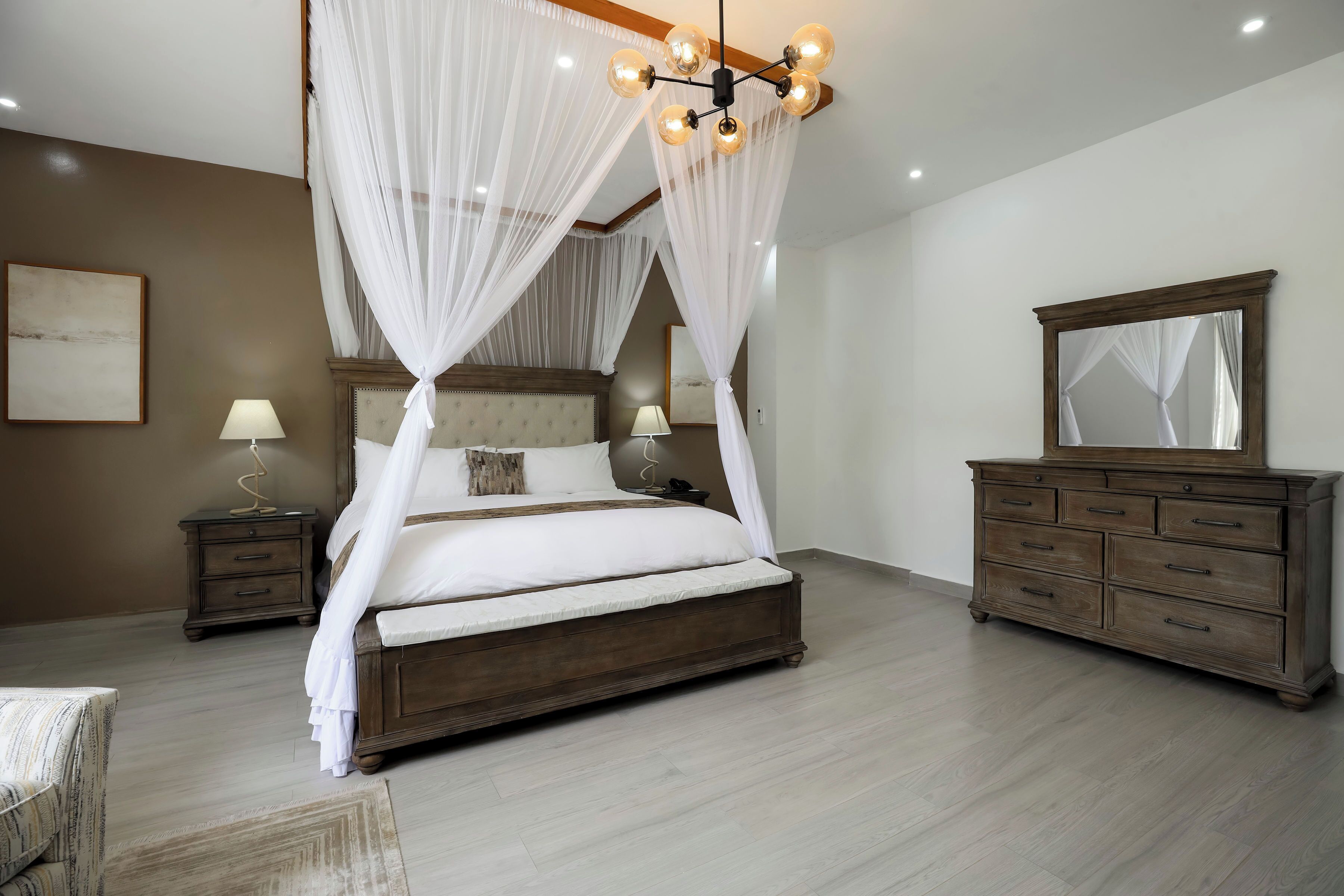 Un dormitorio con una cama con dosel, cómoda de madera y un espejo grande.