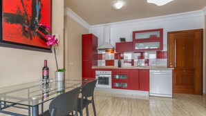 Eine moderne Küche mit roten Schränken, einem Glastisch und einem großen Gemälde in Rot und Schwarz an der Wand.