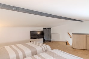 Une chambre à coucher avec un lit, une télévision, une armoire et un plancher en bois.