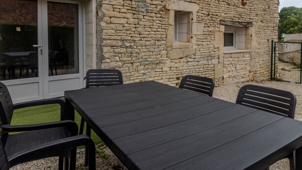 Un bâtiment en pierre doté d’un patio comprenant une table et des chaises.