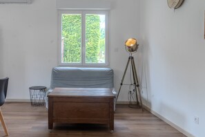 Une pièce avec un lit, une fenêtre, une lampe sur pied et une petite table d’appoint.