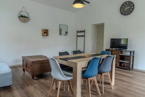 A modern dining area with a wooden table, blue and white chairs, a small cabinet, and a television on a stand. - Holiday Home 'Berclois' with Private Terrace, Wi-Fi and Air Conditioning (Bercloux)