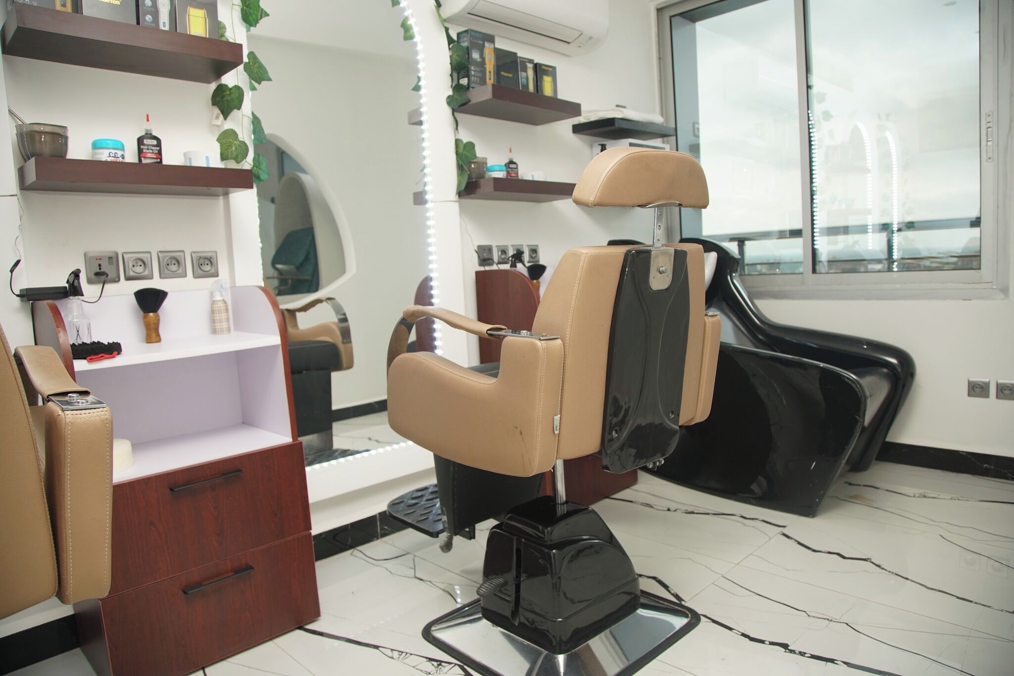 Un salone di bellezza con una poltrona professionale nera, un mobiletti in legno e scaffali con prodotti per capelli.