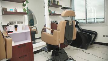 Un salone di bellezza con una poltrona professionale nera, un mobiletti in legno e scaffali con prodotti per capelli.