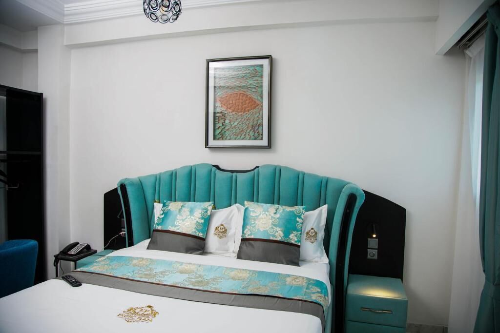 A hotel room with a bed, a bedside table, a phone, and a wall-mounted artwork.