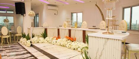 A modern hotel lobby with a marble floor, a reception desk, and a large chandelier.