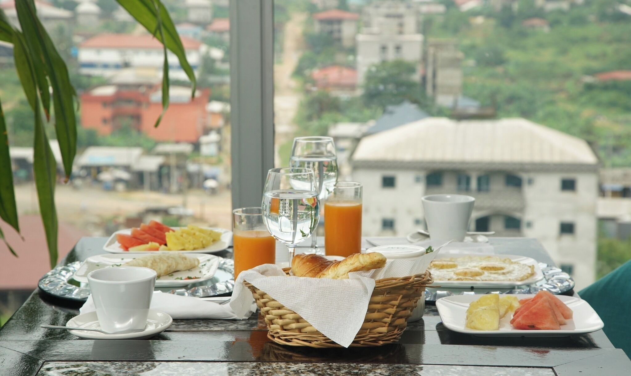 A breakfast table with plates of food, glasses of orange juice, and a basket of bread.