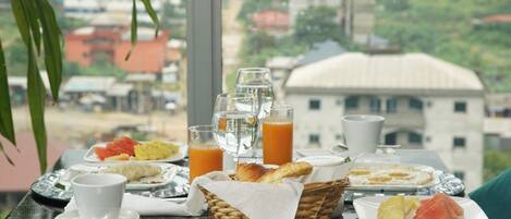 A breakfast table with plates of food, glasses of orange juice, and a basket of bread.