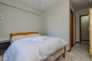 Un dormitorio con una cama individual, cabecera de madera y pared blanca.